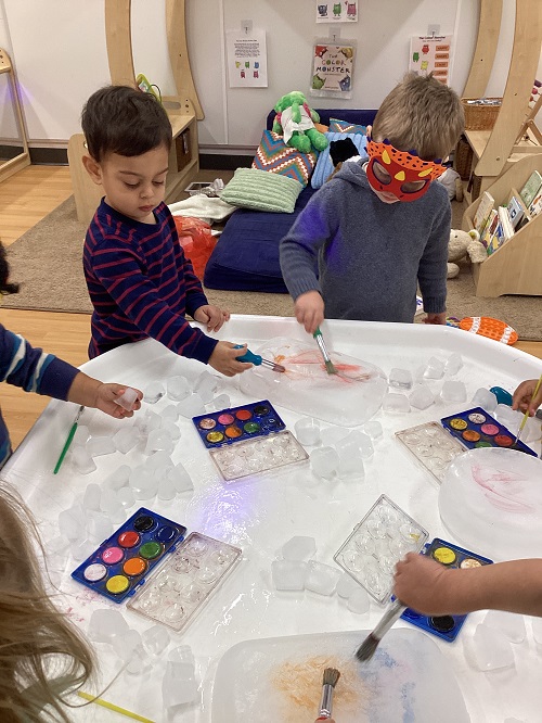 A small group of children exploring with paint and ice.