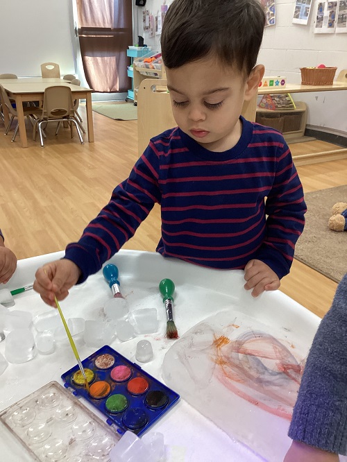 A small group of children exploring with paint and ice.