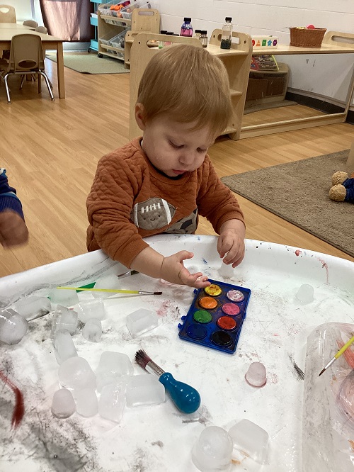 A child exploring with paint and ice.