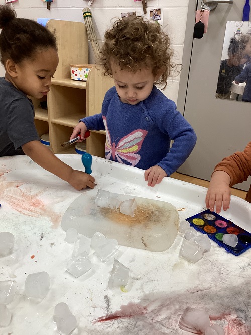 A small group of children exploring with paint and ice.