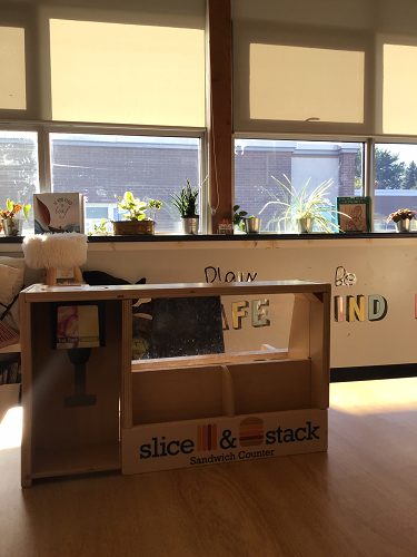 Image of a "Slice and Stack" sandwich counter on a table with classroom items in the background