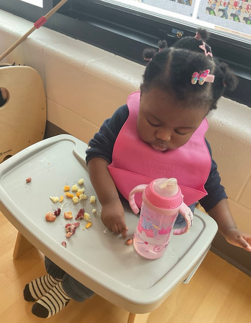 little girl in highchair with beans