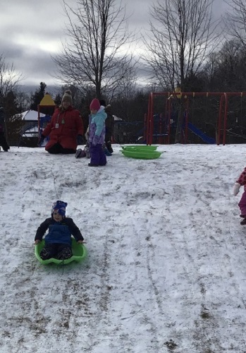 A group of children sledding down the hill