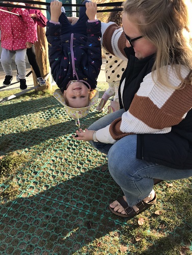 A child hanging upside down close to the educator