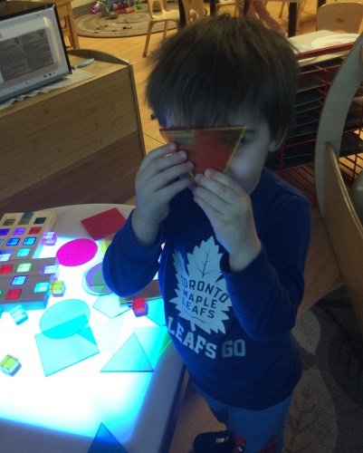 A child looking through coloured translutent tiles