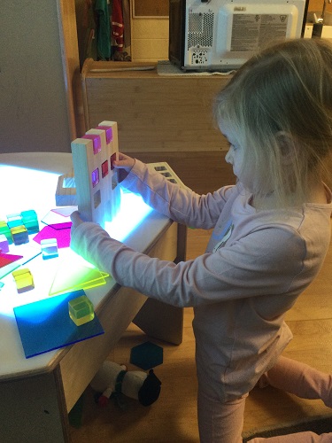 Child looking at translutent coloured blocks