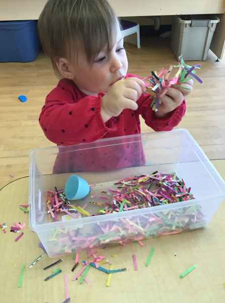 girl finding easter eggs in a bin with shredded paper