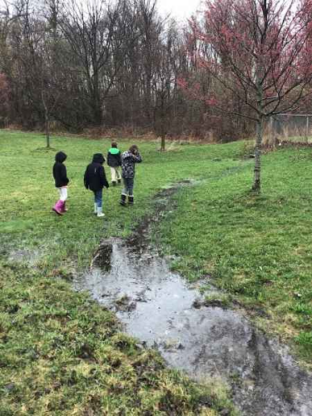 school-age kids walking in the field on a rainy day