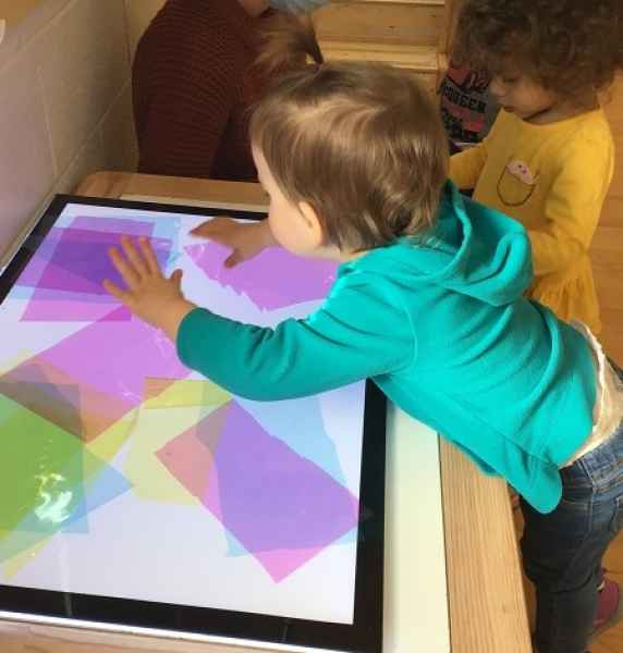 toddlers observing coloured paper on a light table