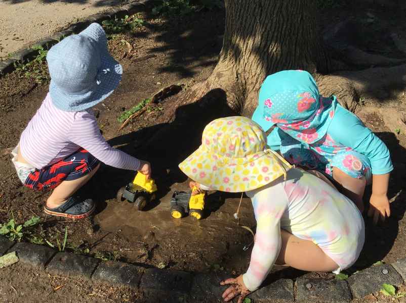 toddlers playing with trucks in the mud