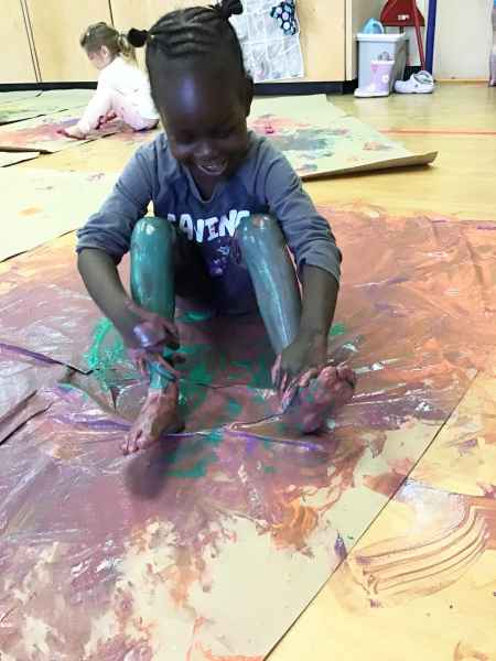 child sitting in and covered with paint