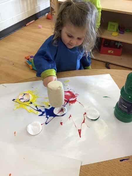 child using a play hammer to make a splatter painting