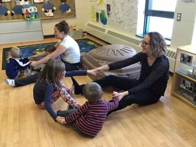 children and educators doing yoga while holding hands