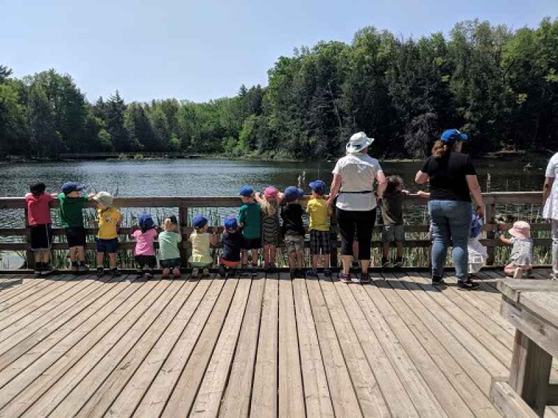 preschool children standing on a boardwalk looking over a lake