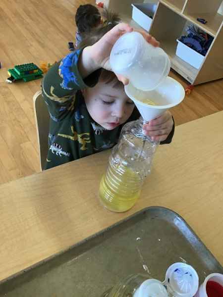 boy pouring liquid through a funnel into a bottle