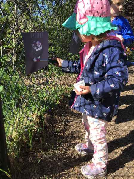 girl painting on paper hung on a fence