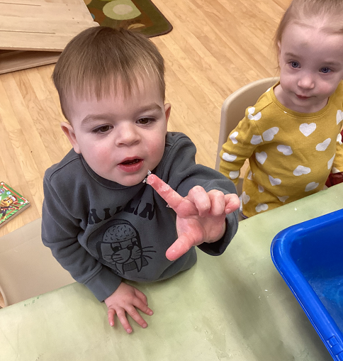 child holding up a finger that has melting snow on it
