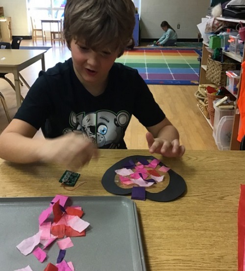 child at table working on a valentines day craft