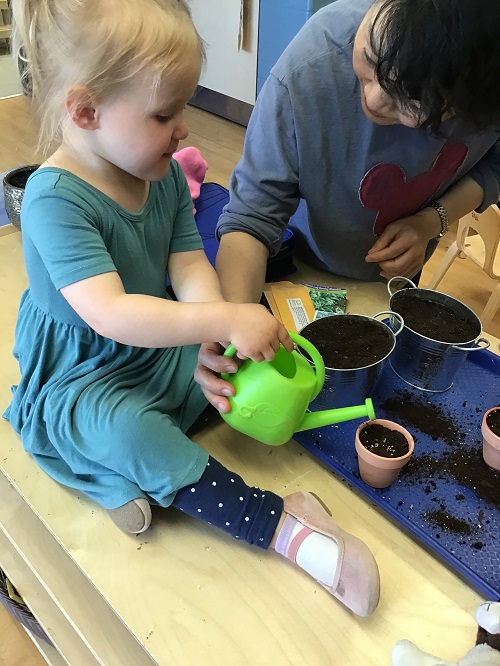 Child and educator watering plants