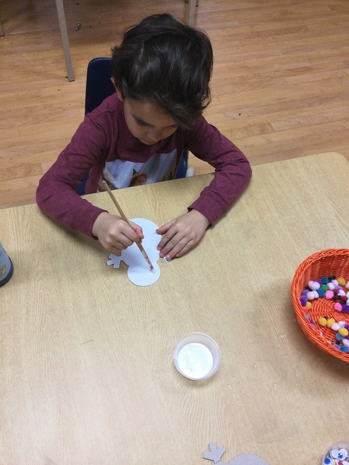 Boy decorating white snowman