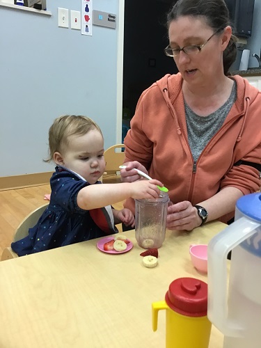 Educator assisting child with pouring water