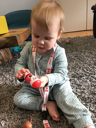 An infant is placing a Santa finger puppet on their finger.