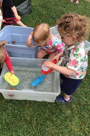 Toddlers are adding objects to buckets filled with water to see if they sink or float.