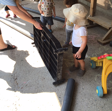 A toddler educator and some toddlers are setting up their toddler track.