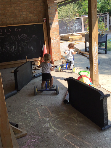 Two toddlers are riding bikes through their toddler track.