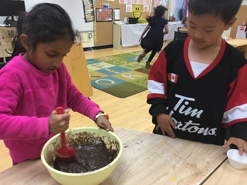 2 school-age children mixing cupcake batter 