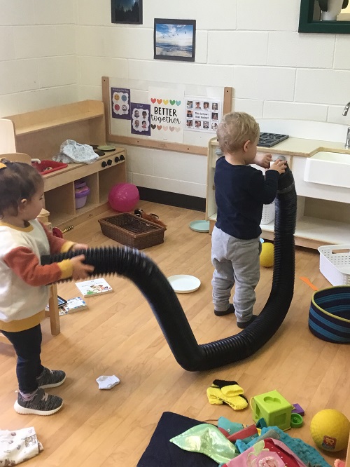 two children putting toys into a tube