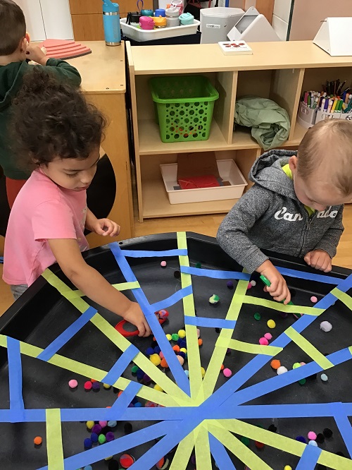 Children putting pom poms through holes