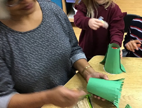 child working with educator to make puppet