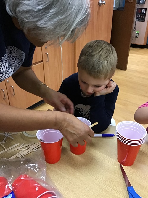 child mixing their solution alongside an educator