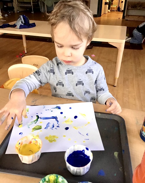 child painting a picture using their finger