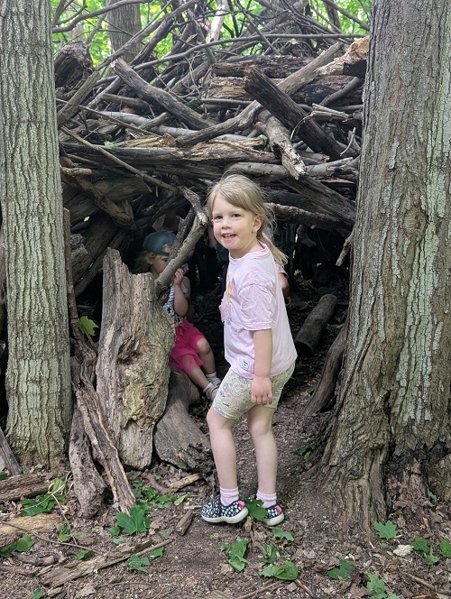 child exploring a wooden tepee fort