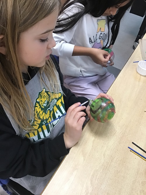 child painting ornament with paint brush