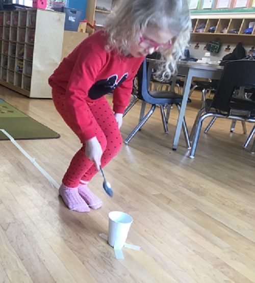 child putting pom pom into cup
