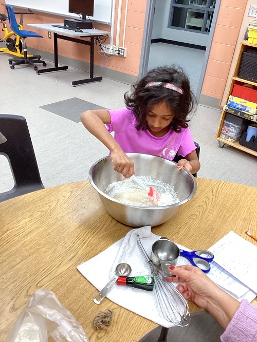 child placing ingredients into a bowl
