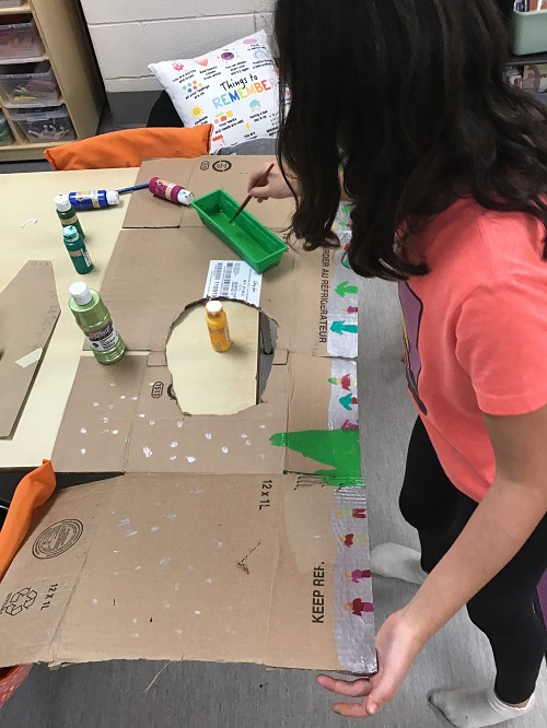 child gluing paper onto their board game