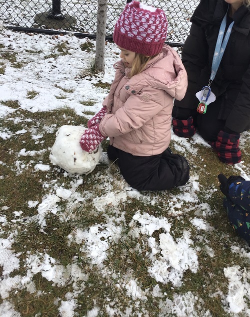 Child rolling a snowball.