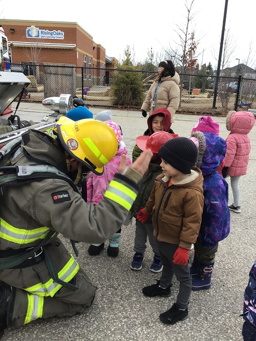 Children observing Fire Fighter's helmet. 