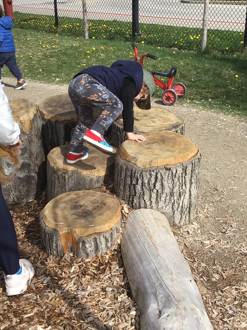 Child climbing on the logs. 
