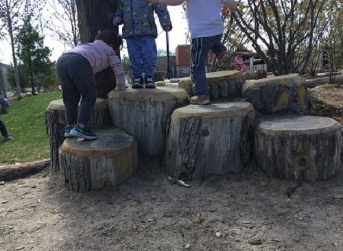Toddlers climbing the logs.