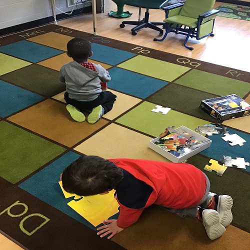 Children doing puzzles on the carpet. 