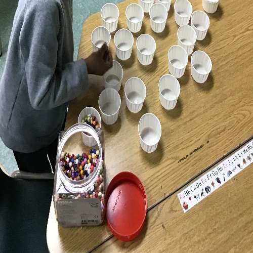 Child placing beads in a cup. 