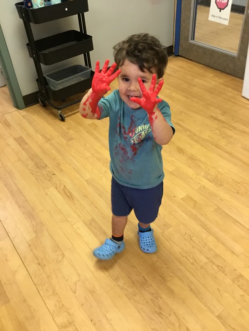 Child showing their red painted hands. 