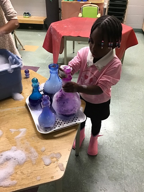 Child observing water in the coloured bottle.