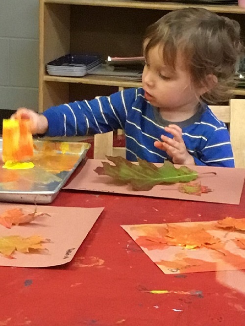 Child painting with autumn leaves