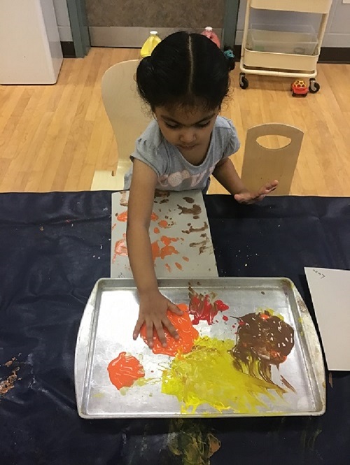 Child painting with autumn leaves